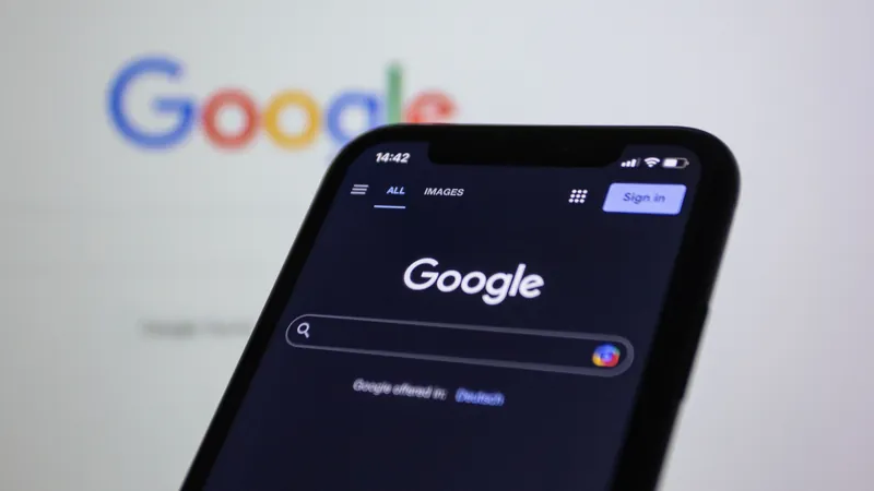 Un smartphone affiche la page d'accueil de Google, devant le logo Google flou en arrière-plan