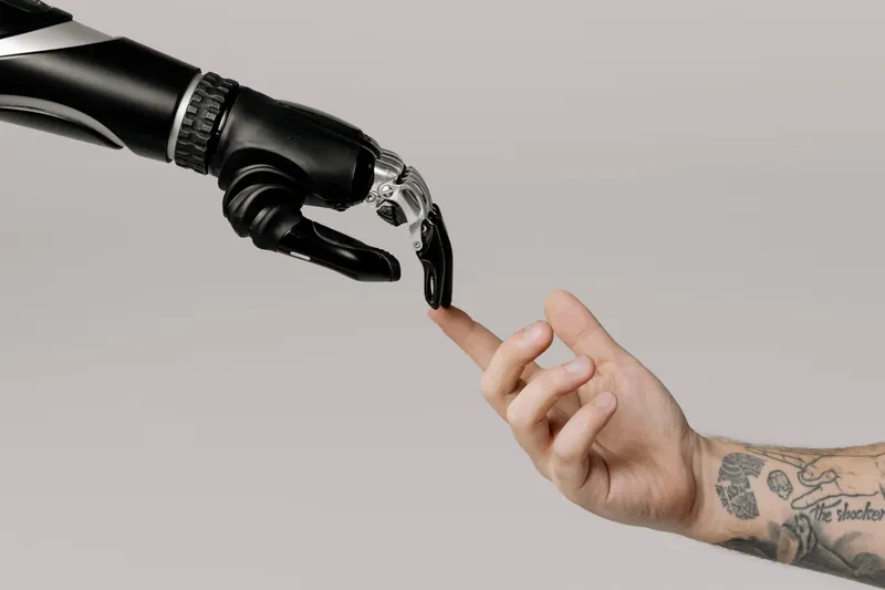 Une main robotique et une main humaine se tendent l'index, à la manière de La Création d'Adam